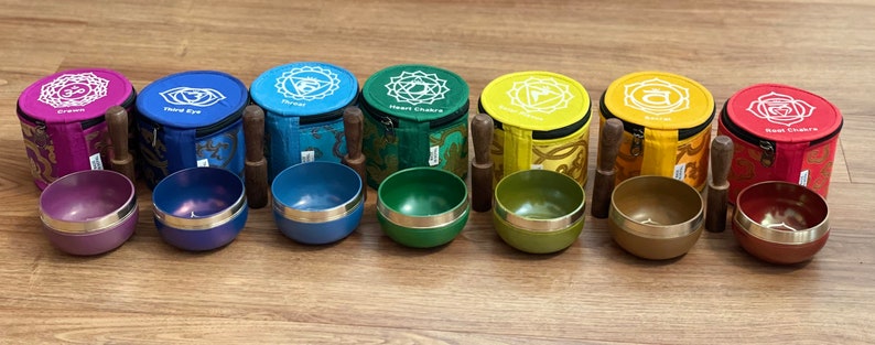 May include: Set of seven singing bowls with mallets and colorful fabric carrying cases. Each bowl is decorated with a different chakra symbol and color.