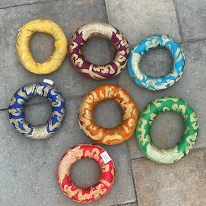Puede incluir: Siete cojines de meditaci&oacute;n coloridos, cada uno con un patr&oacute;n y un color diferente. Los cojines son redondos y tienen un agujero en el centro. Est&aacute;n hechos de tela y tienen una textura suave y c&oacute;moda.