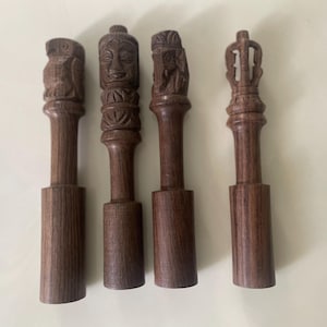 Könnte beinhalten: Vier dekorative Holzabschlüsse mit verschiedenen geschnitzten Designs. Die Abschlüsse sind braun und haben eine glatte Oberfläche.