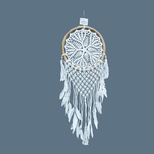 May include: White dream catcher with a wooden hoop and white feathers. The dream catcher has a crocheted design and white beads.