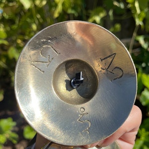 May include: A pair of small, round, brass cymbals with a black string connecting them. The cymbals have the numbers "1" and "2" engraved on them, along with the text "3.5" on the bottom.