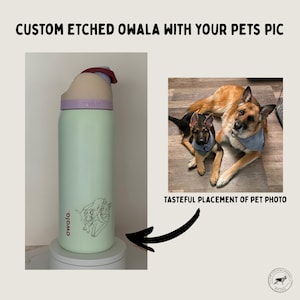 May include: A mint green Owala water bottle with a purple lid and a custom etched pet design. The text "CUSTOM ETCHED OWALA WITH YOUR PETS PIC" is at the top. The bottle is on a white stand. The image also includes a photo of two dogs.
