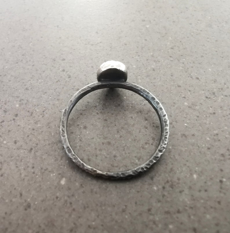 May include: A silver ring with a textured band and a round, hammered silver top.