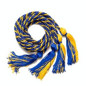 May include: A blue and gold graduation cord with three tassels. The cord is twisted and has a braided design. The tassels are made of the same blue and gold colors.