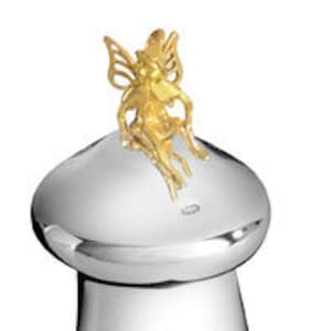 Könnte beinhalten: Ein silberfarbener, pilzförmiger Behälter mit einer goldfarbenen Feenfigur auf der Oberseite. Der Behälter hat eine glatte, reflektierende Oberfläche und einen zylindrischen Sockel. Die Fee hat detaillierte Flügel und sitzt.