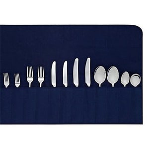 Może przedstawiać: Niebieski wałek z tkaniny z kieszeniami na sztućce. Wałek zawiera widelce, noże i łyżki.