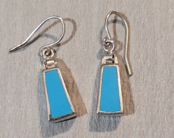 May include: A pair of silver dangle earrings with turquoise blue rectangular stones.