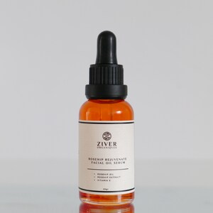 May include: A clear glass bottle with a black dropper top filled with a light orange liquid. The bottle is labeled "ZIVER ORGANIQUES ROSEHIP REJUVENATE FACIAL OIL SERUM" and lists the ingredients as "ROSEHIP OIL, ROSEHIP EXTRACT, VITAMIN E". The bottle contains 30 grams of product.