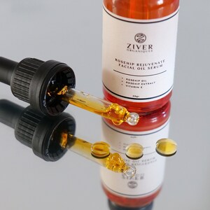May include: A glass bottle of rosehip facial oil serum with a dropper. The bottle is labeled "Ziver Organiques Rosehip Rejuvenate Facial Oil Serum" and lists the ingredients as rosehip oil, rosehip extract, and vitamin E.