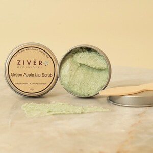 Puede incluir: Un peque&ntilde;o bote de exfoliante labial de manzana verde con una esp&aacute;tula de madera. El bote est&aacute; etiquetado con "ZIVER ORGANIQUES Exfoliante labial de manzana verde Vegano Libre de aceite de palma Sostenible 15gr".