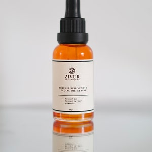 May include: A 30-gram amber glass bottle of rosehip rejuvenate facial oil serum with a black dropper top. The label is white with black text that reads "Ziver Organiques Rosehip Rejuvenate Facial Oil Serum" and lists the ingredients: "Rosehip Oil, Rosehip Extract, Vitamin E".