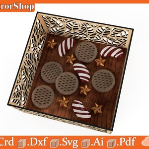 Op de afbeelding: Een houten dienblad met een decoratief uitgesneden ontwerp, gevuld met chocoladekoekjes, rode en witte snoepstokken en gouden sterren.