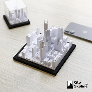 Puede incluir: Modelo 3D de un horizonte urbano, con edificios blancos sobre una base negra. El modelo presenta rascacielos y otras estructuras arquitect&oacute;nicas. Una versi&oacute;n en miniatura est&aacute; dentro de un cubo transparente. El logotipo de City Skyline 3D es visible.