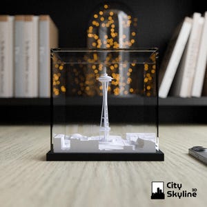 May include: A white 3D model of the Seattle Space Needle and surrounding buildings, encased in a clear acrylic box with a black base. The City Skyline 3D logo is visible in the lower right corner.