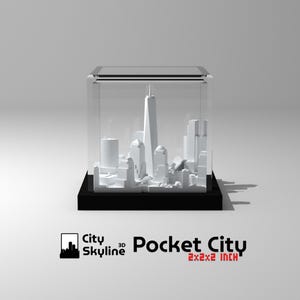 K&ouml;nnte beinhalten: Ein wei&szlig;es 3D-gedrucktes Modell einer Stadtlandschaft in einem durchsichtigen Acryl-W&uuml;rfel. Der W&uuml;rfel steht auf einem schwarzen Sockel. Der Text "City Skyline 3D Pocket City 2x2x2 inch" ist unter dem W&uuml;rfel aufgedruckt.