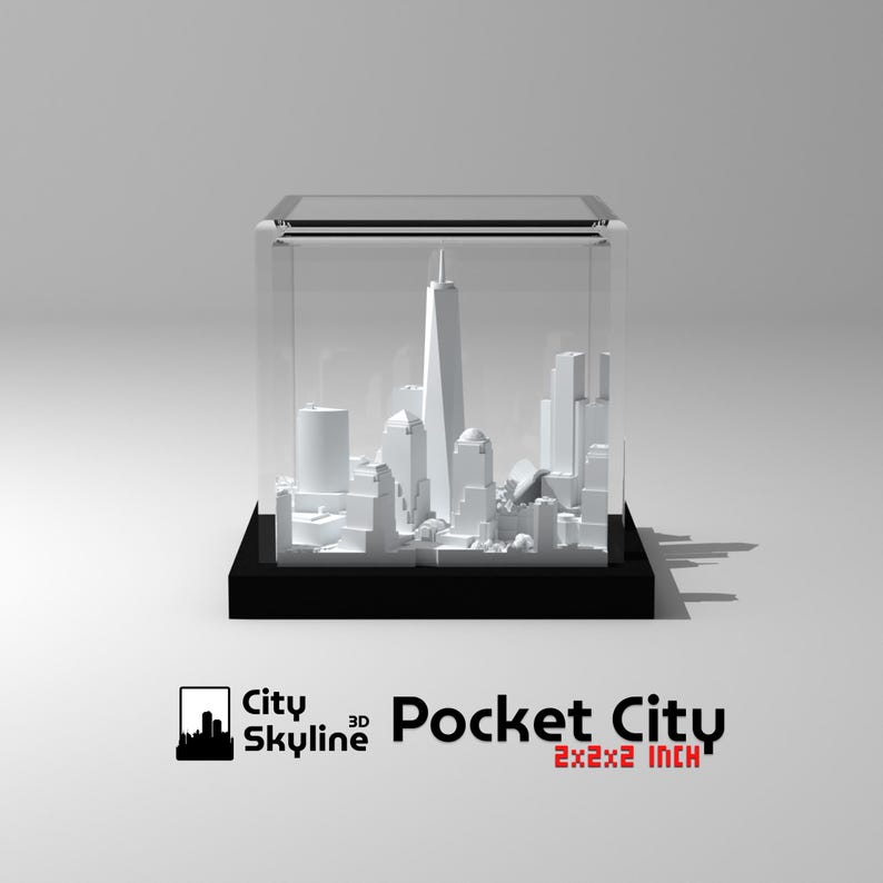 K&ouml;nnte beinhalten: Ein wei&szlig;es 3D-gedrucktes Modell einer Stadtlandschaft in einem durchsichtigen Acryl-W&uuml;rfel. Der W&uuml;rfel steht auf einem schwarzen Sockel. Der Text "City Skyline 3D Pocket City 2x2x2 inch" ist unter dem W&uuml;rfel aufgedruckt.