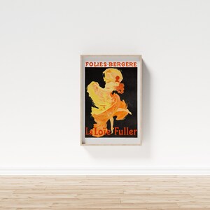 May include: A vintage poster advertising a performance by La Loie Fuller at the Folies-Berg&egrave;re. The poster features a black background with a silhouette of a woman in a flowing yellow and orange dress, dancing on stage.
