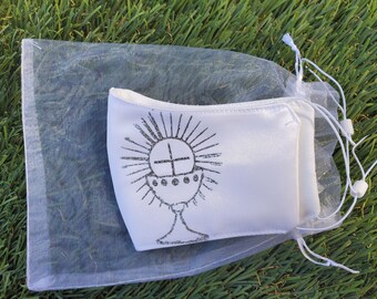 May include: White satin face mask with a black and white image of a chalice and host, a symbol of the Eucharist, in a white organza bag.