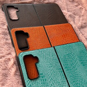 Peut inclure: Trois étuis de téléphone différents avec un motif en peau de crocodile. Les étuis sont marron, orange et turquoise.