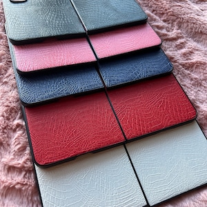 May include: A stack of six phone cases with a crocodile skin pattern. The cases are in black, pink, blue, red, and white.
