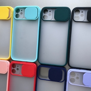 May include: Assortment of phone cases with different colored camera lens covers. The cases are made of clear plastic with a frosted finish. The camera lens covers are made of silicone and come in a variety of colors, including yellow, blue, green, black, pink, red, navy blue, and light blue.