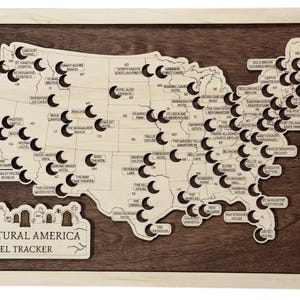 May include: A wooden map of the USA, featuring cut-out locations and labels, set against a dark brown backdrop and framed in light wood. The text "Supernatural America Travel Tracker" is displayed at the bottom of the map.