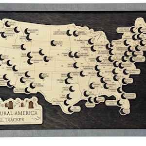 May include: Wooden map of the United States in a grey frame, with cut-out shapes and labels marking locations. The map includes the text "Supernatural America Travel Tracker" at the bottom.