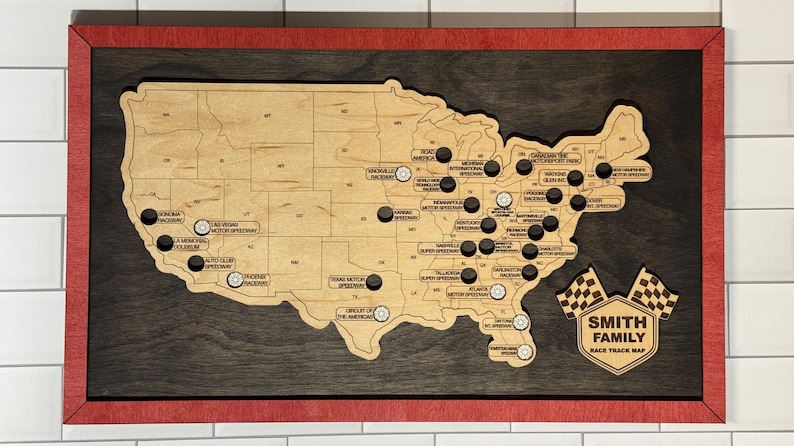 May include: Wooden race track map of the United States with a red frame. The map is laser-cut with state outlines and race track locations marked with black and silver pins. Includes a family name and checkered flag graphic.