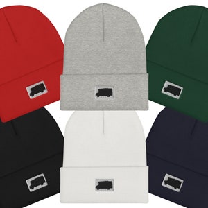 May include: Six beanies in a range of colours: red, grey, green, black, white, and navy. Each beanie has a small rectangular patch with a black truck silhouette.