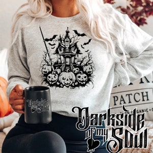 May include: A grey sweatshirt featuring a black and white graphic of a spooky house with bats and pumpkins. The text "Darkside of my Soul" is printed on the bottom of the sweatshirt.