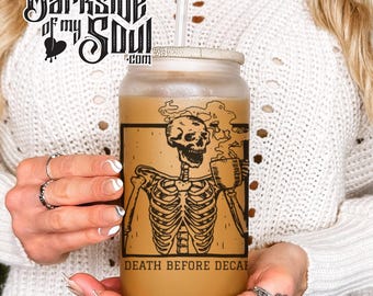 May include: A clear glass tumbler with a brown lid and a black and white illustration of a skeleton drinking coffee. The text "Death Before Decaf" is printed on the tumbler.