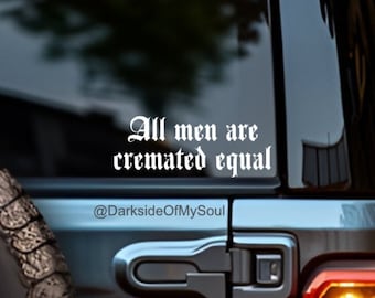 Op de afbeelding: Witte vinyl sticker op een zwarte auto met de tekst "All men are cremated equal" in gotische letter. De tekst wordt gevolgd door de social media handle "@DarksideOfMySoul".