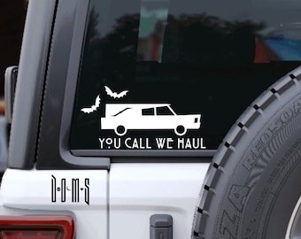 May include: White vinyl sticker on the back window of a white Jeep. The sticker shows a hearse with bats flying above it and the text "You call we haul".