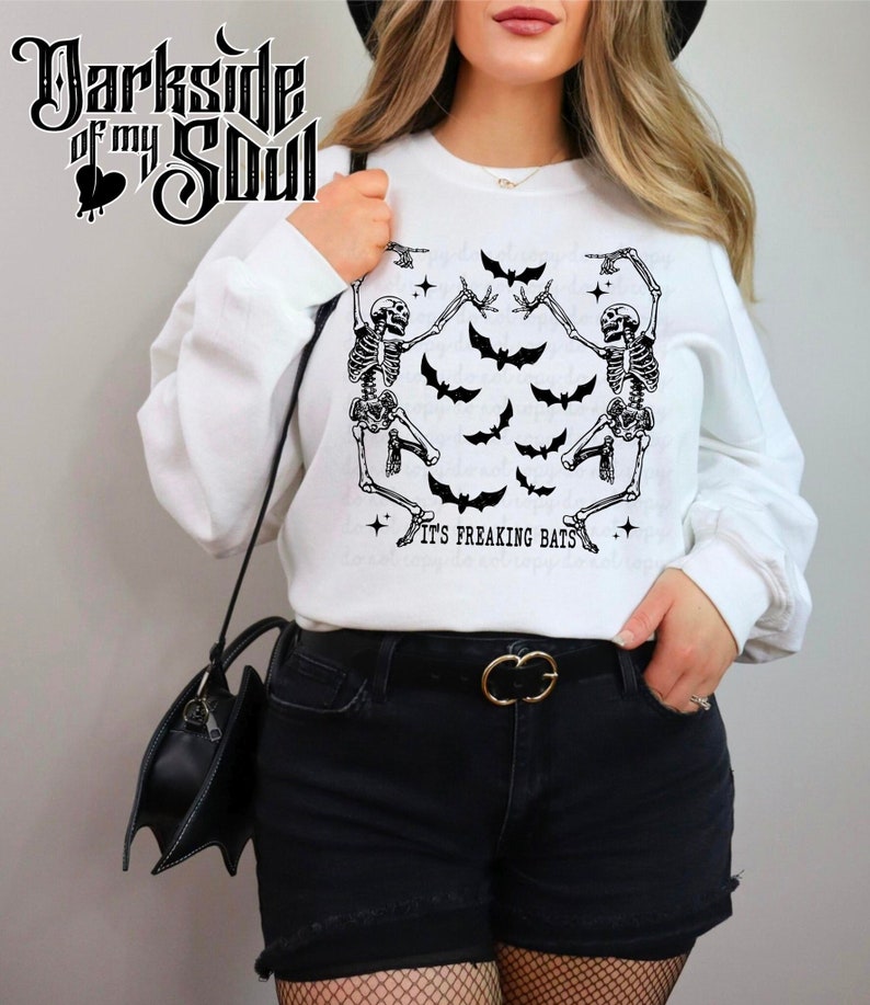 May include: White sweatshirt with a graphic of two skeletons dancing with bats and the text "It's Freaking Bats".