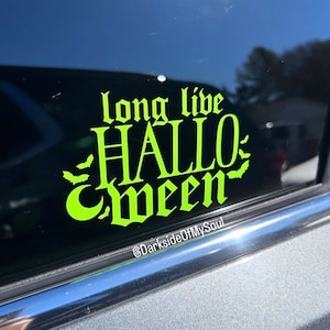 May include: A green vinyl sticker with the text "long live HALLOWEEN" in a gothic font. The sticker has a crescent moon and bats around the text. The text "@DarksideOfMySoul" is at the bottom of the sticker.