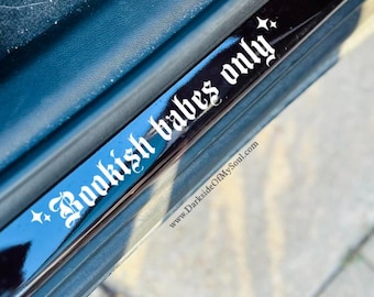 Op de afbeelding: Een zwarte en blauwe autodeurlijst met de witte gotische tekst "Bookish babes only". De lijst heeft een reflecterend oppervlak en is versierd met kleine sterren. Het websiteadres www.DarksideOfMySoul.com is ook zichtbaar.