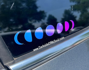 May include: A car window with a sticker of a crescent moon in various shades of blue and purple, with the text "www.DarksideOfMySoul.com" below.