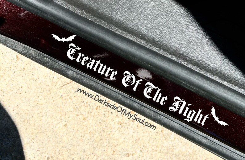 May include: A black and white decal with the text "Creature of the Night" and two bat silhouettes. The decal is on a black and red surface. The website address "www.DarksideOfMySoul.com" is printed below the text.