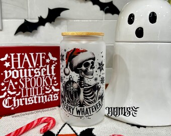 May include: A frosted glass tumbler with a bamboo lid features a skeleton wearing a Santa hat and holding an ornament, with the text "MERRY WHATEVER." A red sign reads "Have Yourself A Spooky Little Christmas."