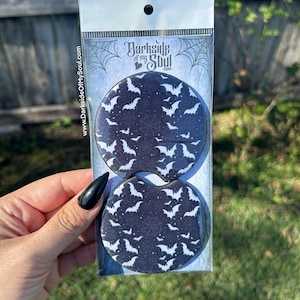 May include: Two black and white round coasters with a pattern of white bats on a black background. The coasters are packaged in a clear plastic bag with a white header card that says "Darkside of my Soul.com".