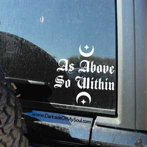May include: White vinyl sticker with the text "As Above So Within" in a gothic font. The sticker also features two crescent moons with a star in the center. The sticker is on a black car window. The website www.DarksideOfMySoul.com is visible below the sticker.