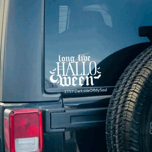 May include: A white vinyl decal with the text "long live HALLOWEEN" in a gothic font with bats on either side. The decal is on the back window of a black Jeep. The text "ETSY-DarksideOfMySoul" is below the decal.