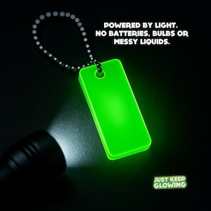Glow in the dark keychain charging with bright flashlight – reusable light source powered by any light.