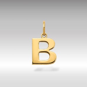 Może przedstawiać: Złoty wisiorek z literą "B" z pętlą na łańcuszek. Wisiorek ma jednolity, błyszczący złoty kolor i jest zaprojektowany klasyczną czcionką szeryfową. Tło to gradient jasnoszary.