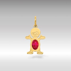 Puede incluir: Colgante dorado con forma de persona estilizada con los brazos extendidos. El colgante presenta una gran gema roja brillante de forma ovalada en el centro. Tiene un lazo en la parte superior para una cadena.