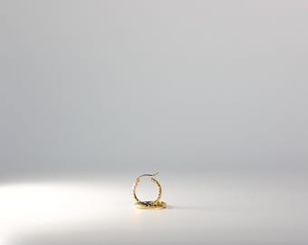 May include: Gold hoop earrings with a textured surface.