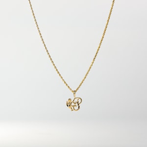 May include: A gold chain necklace with a pendant featuring a stylized letter 'B' with an angel design.