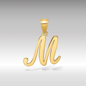 Könnte beinhalten: Ein goldfarbener Anhänger in Form des Buchstabens "M" in Schreibschrift. Der Anhänger hat oben eine Schlaufe für eine Kette. Der Hintergrund ist ein Farbverlauf von hellgrau zu weiß.