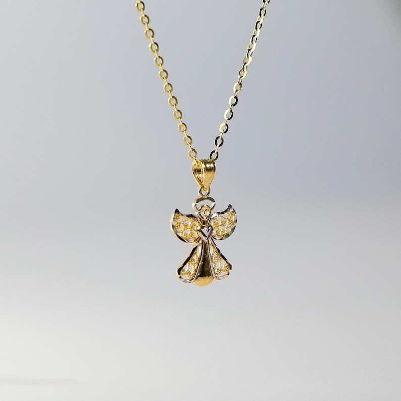 May include: A gold and silver angel pendant necklace. The angel has delicate wings and a heart in the center of its chest.