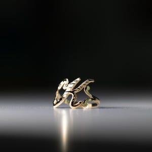 K&ouml;nnte beinhalten: Ein goldener Ring mit einem filigranen, komplizierten Design. Der Ring besteht aus einem einzigen St&uuml;ck Metall und hat eine glatte, polierte Oberfl&auml;che.